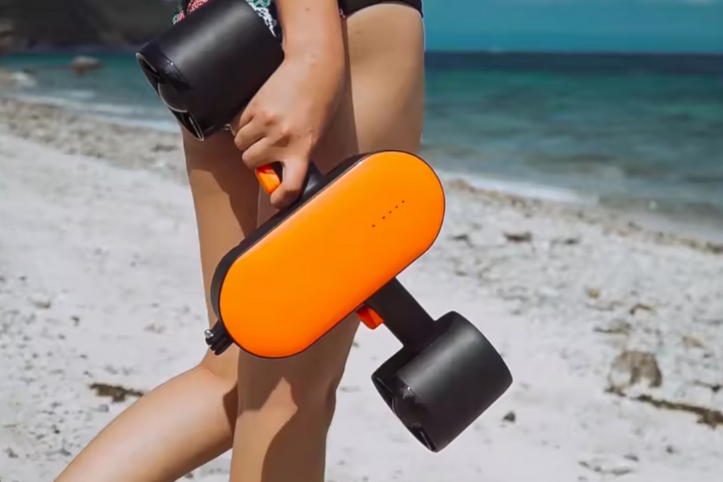 Person holding an electric skateboard on a beach